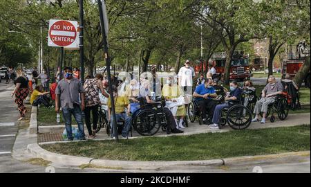 Menschen aus dem Seniorenheim blicken vom Boulevard aus, während das Feuer vom Historic House am 27. April 2021 auf dem Palmer Square, Chicago, USA, wütet. Ein Hausbrand brach in der 2228 N. Kedzie Avenue auf dem Palmer Square bei ca. 3:45pm CST aus. Der Brand wurde vermutlich durch Bauarbeiten auf dem Dachboden und auf dem Dach verursacht. Ein einziger Arbeiter kämpfte gegen das Feuer, bis die Feuerwehr von Chicago am Tatort eintraf. Ein angrenzendes Altenheim wurde aus Sicherheitsgründen evakuiert. Die Frau, die in der Residenz lebte, entkam unverletzt, und ein Feuerwehrmann wurde von EMS mit lebensbedrohlichen Verletzungen weggebracht. (Foto von Jim Vondruska Stockfoto