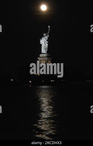 Der Super Flower Moon steigt am 27. April 2021 hinter der Freiheitsstatue in New York City, USA, aus der Sicht von Jersey City, New Jersey, auf. (Foto von Deccio Serrano/NurPhoto) Stockfoto