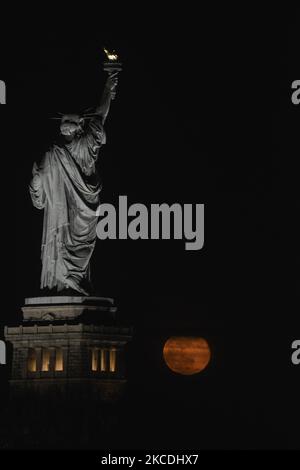 Der Super Flower Moon steigt am 27. April 2021 hinter der Freiheitsstatue in New York City, USA, aus der Sicht von Jersey City, New Jersey, auf. (Foto von Deccio Serrano/NurPhoto) Stockfoto