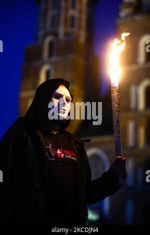 Ein Protestant hält eine Fackel, während er am 28. April 2021 an der regierungsfeindlichen Demonstration „List of Shame“ auf dem Hauptplatz in Krakau, Polen, teilnimmt. Der Protest wurde von Mitgliedern der Initiative „No More Silence“ organisiert, die die Namen von polnischen rechtsextremen Politikern, darunter den polnischen Präsidenten Andrzej Duda, Premierminister Mateusz Morawiecki und den regierenden Parteivorsitzenden Jaroslaw Kaczynski, aufzählten und verurteilten. (Foto von Beata Zawrzel/NurPhoto) Stockfoto