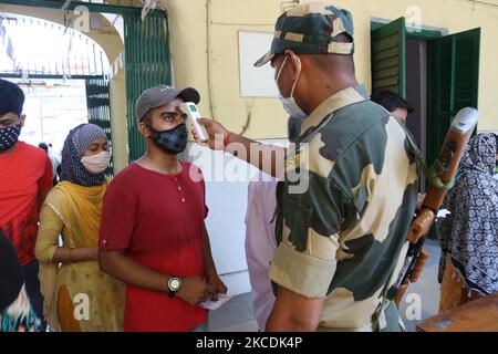 Ein paramilitärisches Personal überprüft die Körpertemperatur einer Frau, die eine Maske trägt, vor ihrer Wahl in einem Wahllokal während der Phase 8. der Wahlen zur Versammlung in Westbengalen am 29. April 2021 in Kalkutta, Indien. Die Phase der Wahlen zur Westbengalischen Versammlung 8. 2021 steht vor der Pandemie des Covid-19 Coronavirus. (Foto von Debajyoti Chakraborty/NurPhoto) Stockfoto