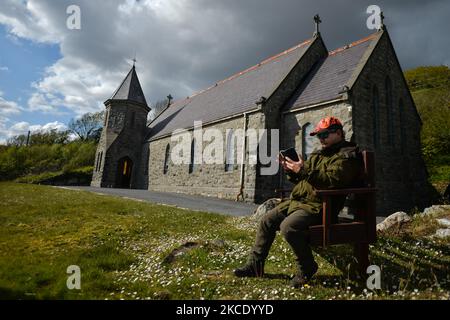 Pater Krzysztof Sikora überprüft sein Mobiltelefon vor der St. James's Church in Cashel, Connemara. Die Gemeinde Roundstone gilt geografisch als die größte Gemeinde Irlands und erstreckt sich von den Stränden von Gurteen bis zu den zwölf Bens und dem Mám Tuirc-Gebirge. Bis zum 1990s wurde die Pfarrei von drei Priestern gedient, jetzt gibt es nur noch einen, der fünf Kirchen betreut. Der derzeitige Pfarrer, ein gebürtiger polnischer Pater Krzysztof Sikora, ist Mitglied der Ordensgemeinschaft der Missionare des Göttlichen Wortes. Nach Jahren als Missionar auf den Philippinen, in Deutschland und in Polen ließ er sich in Irland nieder Stockfoto