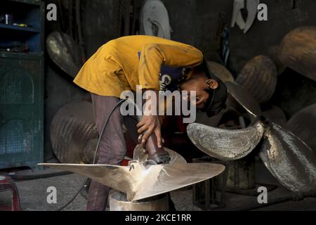 Während einer Pandemie arbeiten Kinder und Arbeiter am Mittwoch, den 5. Mai 2021, in der Werft in der Nähe des Buriganga River in Dhaka, Bangladesch, gefährliche Arbeiten. Die Schiffbauindustrie in Bangladesch breitet sich schnell aus, wo Arbeiter jeden Alters zusammenarbeiten. Der Zustand, in dem das Hotel funktioniert, ist kein Witz und für Kinder nicht angemessen. Die Bedingungen sind heiß und regelmäßig unsicher. Tatsächlich nutzen selbst Arbeiter nicht den geringsten Sicherheitsschutz. In diesem Sinne kommt es so oft wie möglich zu Pannen. Kinder, die hier arbeiten, wachsen ohne Training auf, was sie in eine fragwürdige Zukunft treibt. Der Grund für Sie Stockfoto