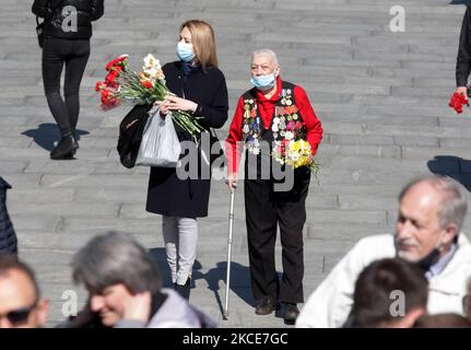 Am 9. Mai 2021 tragen Menschen Blumen zum Denkmal des ewigen Ruhms auf dem Grab des unbekannten Soldaten, während der Feier des Sieges inmitten des Covid-19-Coronavirus-Ausbruchs in Kiew, Ukraine. Die Ukrainer gedenken des 76.. Jahrestages des Sieges über Nazi-Deutschland im Zweiten Weltkrieg (Foto von STR/NurPhoto) Stockfoto