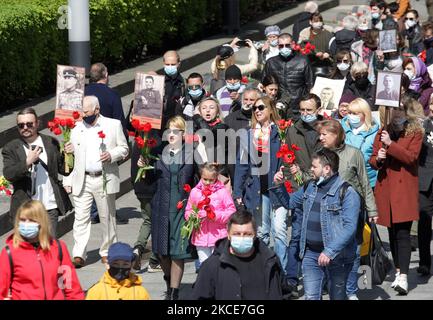 Während der Feier des Siegesfestes am 9. Mai 2021, bei der der Ausbruch des Covid-19-Coronavirus in Kiew, Ukraine, stattfand, tragen Menschen Blumen zum Denkmal des ewigen Ruhms auf dem Grab des unbekannten Soldaten. Die Ukrainer gedenken des 76.. Jahrestages des Sieges über Nazi-Deutschland im Zweiten Weltkrieg (Foto von STR/NurPhoto) Stockfoto