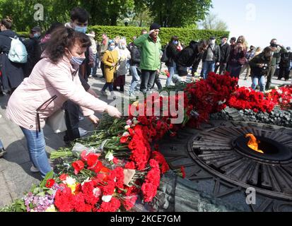 Am 9. Mai 2021 tragen Menschen im Rahmen der Feier des Sieges im Rahmen des Covid-19-Coronavirus-Ausbruchs in Kiew, Ukraine, Laienblumen zum Denkmal des ewigen Ruhms am Grab des unbekannten Soldaten. Die Ukrainer gedenken des 76.. Jahrestages des Sieges über Nazi-Deutschland im Zweiten Weltkrieg (Foto von STR/NurPhoto) Stockfoto
