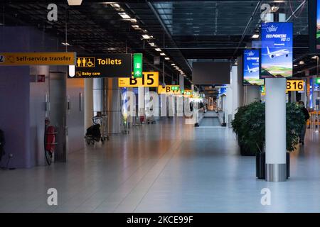Während der Pandemie von Covid-19 ist der Bereich der Abflugtore im Terminal des internationalen Flughafens Amsterdam Schiphol fast leer. Die Anzahl der Passagiere und die Crew tragen Schutzausrüstung wie die obligatorischen Gesichtsmasken und Handschuhe, um die Ausbreitung des Coronavirus zu vermeiden. Die Zahl der Passagiere im Weltflug sank aufgrund der Reisebeschränkungen, Sicherheitsmaßnahmen wie Sperren, Quarantäne, PCR und Schnelltests vor den Flügen während der Ära der Coronavirus-Pandemie Covid-19, die die Luft- und Reisebranche schwer getroffen hatte. Amsterdam Stockfoto