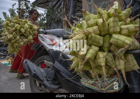 Ein saisonaler Händler bringt am 11. Mai 2021 an einem Stall im Hauptmarktgebiet Manonda, Palu, Zentral-Sulawesi, Indonesien, Ketupat-Bestellungen für Käufer vor Eid Eid al-Fitr ein. Ketupat ist ein typisches Essen, das während des Eid aus Reis serviert wird und in einem Behälter aus gedämpften Pandanblättern oder Kokosnussblättern aufbewahrt wird. Hunderte von Saisonhändlern kommen am Fuße des Mount Gawalise, etwa 5 Kilometer vom Marktstandort entfernt, und handeln vor Eid al-Fitr verschiedene Lebensmittelbedürfnisse wie Ketupat und Gewürze oder Zutaten zum Kochen von Gewürzen. Die Waren sind ihre landwirtschaftlichen Erzeugnisse am Fuße des Berges Stockfoto