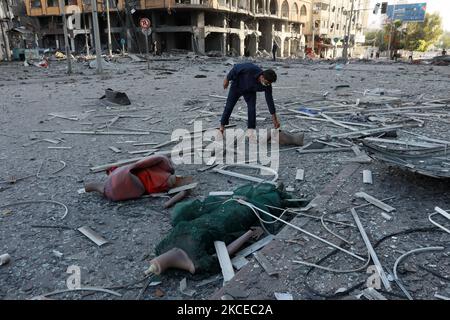 Ein Palästinenser inspiziert die Trümmer Anfang des 12. Mai 2021 vor dem schwer beschädigten Al-Jawhara-Turm in Gaza-Stadt, der über Nacht von israelischen Luftangriffen getroffen wurde. - Israelische Luftangriffe im Gazastreifen haben die Häuser hochrangiger Mitglieder der militanten Hamas-Gruppe getroffen, teilte das Militär am Mittwoch mit, wobei auch das Polizeihauptquartier des Gebiets gezielt angegriffen wurde. (Foto von Majdi Fathi/NurPhoto) Stockfoto