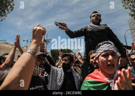 Ein Demonstranten, der auf den Schultern eines Protesters steht, Gesten und Rufe gegen Israel ausruft, während andere Demonstranten während einer Demonstration, die von tausenden tunesischen und palästinensischen Demonstranten auf der Avenue Habib Bourguiba in der Hauptstadt Tunis, Tunesien, am 15. Mai 2021 abgehalten wurde, die Faust erheben. Zur Unterstützung des palästinensischen Volkes und zum Protest gegen die israelischen Luftangriffe auf den Gazastreifen und gegen die israelischen Verletzungen in den besetzten Gebieten Palästinas, insbesondere in der palästinensischen Nachbarschaft in Ostjerusalem, Sheikh Jarrah. (Foto von Chedly Ben Ibrahim/NurPhoto) Stockfoto