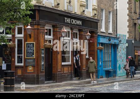 LONDON, VEREINIGTES KÖNIGREICH - 17. MAI 2021: Ein Mitarbeiter steht am 17. Mai 2021 in London, England, vor der Tür eines Pubs im Zentrum Londons und wartet auf Kunden, während England zu Schritt 3 zur Lockerung der Einschränkungen des Coronavirus wechselt. Ab heute dürfen Hallen- und Unterhaltungseinrichtungen wieder geöffnet werden, sechs Personen oder zwei Haushalte können sich in Innenräumen treffen und internationale Reisen ohne Quarantäneantritt in 12 grüne Liste-Länder durchführen, Es bestehen jedoch Bedenken, dass der Anstieg der Fälle der indischen Covid-Variante die vierte Stufe der Lockerung am 21. Juni verzögern könnte. (Foto von Wiktor Szymanow Stockfoto