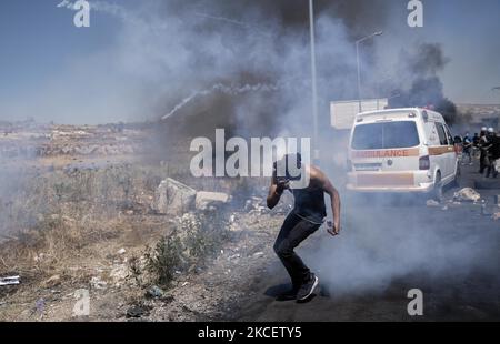 Ein palästinensischer Protestor flüstert vor Tränengas, das israelische Soldaten am 17. Mai 2021 bei Zusammenstößen in der Nähe der jüdischen Siedlung Beit El in der Nähe von Ramallah, Westjordanland, im besetzten Westjordanland abgefeuert haben. (Foto von Ahmad Talat/NurPhoto) Stockfoto