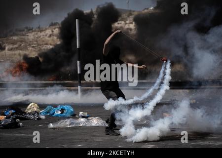 Ein palästinensischer Demonstranten wirft während der Zusammenstöße in der Nähe der jüdischen Siedlung Beit El in der Nähe von Ramallah, Westjordanland, am 17. Mai 2021 im besetzten Westjordanland Tränengaskanister auf israelische Streitkräfte zurück. (Foto von Ahmad Talat/NurPhoto) Stockfoto