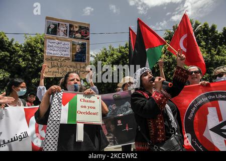 Während einer Demonstration, die am 18. Mai 2021 vor dem Parlamentsgebäude in der tunesischen Stadt Bardo Tunis stattfand, rief eine Protestierenden gegen Israel protestierende Parolen aus und erhob palästinensische und tunesische Flaggen, während ein anderer Protestler ein Plakat mit Fotos von getöteten palästinensischen Kindern aufhebt, Die Verabschiedung eines Gesetzes durch das parlament zu fordern, das alle Formen der Normalisierung der Beziehungen zu Israel kriminalisiert. Die Demonstranten protestierten auch gegen die israelischen Luftangriffe auf den Gazastreifen sowie gegen die israelischen Verletzungen in den besetzten Gebieten Palästinas, insbesondere in den Palästinensern Stockfoto