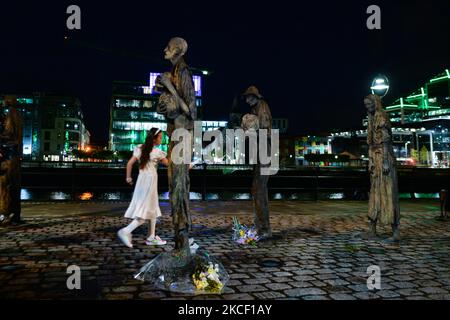 Sadhbh, ein kleines Mädchen, das der verstörten Frauenstatue am Mittwoch, dem 19. Mai, ihre Papiertaube anbietet, um ihr Leiden im Hungersnot Memorial in Dublin zu lindern, als Teil des neuen parallel Peace Project von Herstory, das am Welttag der kulturellen Vielfalt für Dialog und Entwicklung ins Leben gerufen wurde. Syrische, somalische, kenianische und libysche Aktivisten nahmen an einem Projekt in Dublin Teil, das die Geschichte von Frauen und Mädchen auf der irischen Insel erzählt, deren Leben von Kriegen und sozialen Konflikten heimgesucht wurde. Am Donnerstag, den 20. Mai 2021, in Dublin, Irland. (Foto von Artur Widak/NurPhoto) Stockfoto