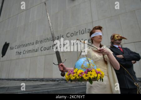 Die Aktivistinnen der Extinction Rebellion, Ceara Carney, kleiden sich mit verbundenen Augen in einem Kleid, während Lady Justice und Louis Heath einen Anzug tragen, um den Staat zu repräsentieren, der während eines theatralischen Protestes auf den Stufen des Strafgerichtshofs in Dublin gesehen wurde, um die Ungerechtigkeit der Klimauntätigkeit zu zeigen, wie die 20-jährige Orla Murphy, Ein Klimaaktivist erscheint vor Gericht wegen strafrechtlicher Schäden. Am Dienstag, den 25. Mai 2021, in Dublin, Irland. (Foto von Artur Widak/NurPhoto) Stockfoto