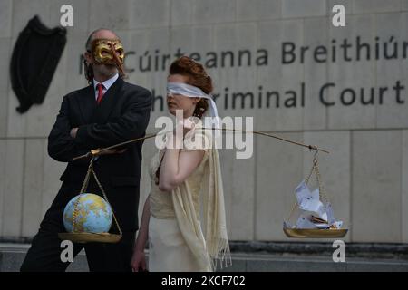 Die Aktivistinnen der Extinction Rebellion, Ceara Carney, kleiden sich mit verbundenen Augen in einem Kleid, während Lady Justice und Louis Heath einen Anzug tragen, um den Staat zu repräsentieren, der während eines theatralischen Protestes auf den Stufen des Strafgerichtshofs in Dublin gesehen wurde, um die Ungerechtigkeit der Klimauntätigkeit zu zeigen, wie die 20-jährige Orla Murphy, Ein Klimaaktivist erscheint vor Gericht wegen strafrechtlicher Schäden. Am Dienstag, den 25. Mai 2021, in Dublin, Irland. (Foto von Artur Widak/NurPhoto) Stockfoto