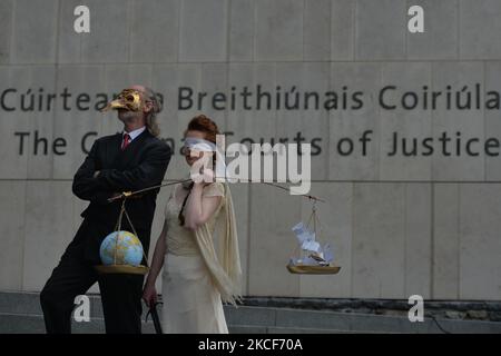 Die Aktivistinnen der Extinction Rebellion, Ceara Carney, kleiden sich mit verbundenen Augen in einem Kleid, während Lady Justice und Louis Heath einen Anzug tragen, um den Staat zu repräsentieren, der während eines theatralischen Protestes auf den Stufen des Strafgerichtshofs in Dublin gesehen wurde, um die Ungerechtigkeit der Klimauntätigkeit zu zeigen, wie die 20-jährige Orla Murphy, Ein Klimaaktivist erscheint vor Gericht wegen strafrechtlicher Schäden. Am Dienstag, den 25. Mai 2021, in Dublin, Irland. (Foto von Artur Widak/NurPhoto) Stockfoto