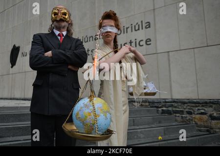 Die Aktivistinnen der Extinction Rebellion, Ceara Carney, kleiden sich mit verbundenen Augen in einem Kleid, während Lady Justice und Louis Heath einen Anzug tragen, um den Staat zu repräsentieren, der während eines theatralischen Protestes auf den Stufen des Strafgerichtshofs in Dublin gesehen wurde, um die Ungerechtigkeit der Klimauntätigkeit zu zeigen, wie die 20-jährige Orla Murphy, Ein Klimaaktivist erscheint vor Gericht wegen strafrechtlicher Schäden. Am Dienstag, den 25. Mai 2021, in Dublin, Irland. (Foto von Artur Widak/NurPhoto) Stockfoto