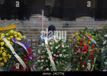 Ein Demonstranten, der seine Identität mit einer Kapuze und einer Brille versteckt, beobachtet den Protest hinter Begräbniskränzen, während sich Menschen auf der Plaza de Bolivar vor dem Kongress-Kapitol versammeln, um den Antrag gegen den kolumbianischen Verteidigungsminister Diego Molano zu unterstützen, nachdem während mindestens 45 Todesfälle in Polizeibrutalitätsfällen während des Kongresses ums stattkamen Die anhaltenden regierungsfeindlichen Proteste gegen Steuer- und Gesundheitsreformen und Polizeibrutalität haben sich in den letzten Wochen in Kolumbien entwickelt, am 24. Mai 2021 in Bogota, Kolumbien. (Foto von Sebastian Barros/NurPhoto) Stockfoto
