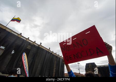Ein Demonstrator hält ein Schild mit der Aufschrift „Diego Molano Genozid“, hinter dem das kolumbianische Kongressgebäude steht, während sich Menschen auf der Plaza de Bolivar vor dem Kongresskapitol versammeln, um den Misstrauensantrag gegen den kolumbianischen Verteidigungsminister Diego Molano zu unterstützen, nachdem mindestens 45 Todesfälle in Polizeibrutalitätsfällen während der Zeit gestorben waren Die anhaltenden regierungsfeindlichen Proteste gegen Steuer- und Gesundheitsreformen und Polizeibrutalität haben sich in den letzten Wochen in Kolumbien entwickelt, am 24. Mai 2021 in Bogota, Kolumbien. (Foto von Sebastian Barros/NurPhoto) Stockfoto