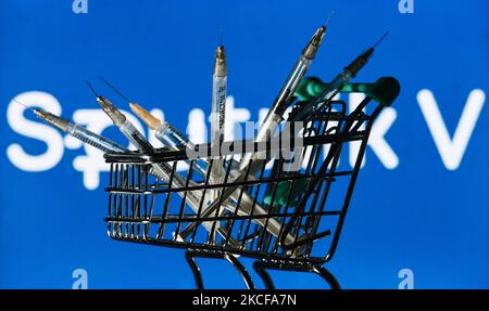 Medizinische Spritzen im Mini-Einkaufswagen sind vor dem Sputnik V-Logo auf einem Bildschirm zu sehen. Am Freitag, den 28. Mai 2021, in Dublin, Irland. (Foto von Artur Widak/NurPhoto) Stockfoto