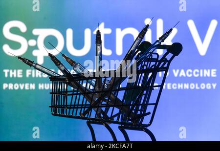 Medizinische Spritzen im Mini-Einkaufswagen sind vor dem Sputnik V-Logo auf einem Bildschirm zu sehen. Am Freitag, den 28. Mai 2021, in Dublin, Irland. (Foto von Artur Widak/NurPhoto) Stockfoto