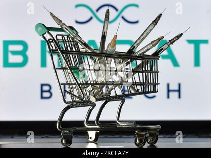 Medizinische Spritzen im Mini-Einkaufswagen sind vor dem Bharat Biotech-Logo auf einem Bildschirm zu sehen. Am Freitag, den 28. Mai 2021, in Dublin, Irland. (Foto von Artur Widak/NurPhoto) Stockfoto