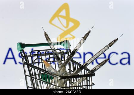 Medizinische Spritzen im Mini-Einkaufswagen sind vor dem AstraZeneca-Logo auf einem Bildschirm zu sehen. Am Freitag, den 28. Mai 2021, in Dublin, Irland. (Foto von Artur Widak/NurPhoto) Stockfoto
