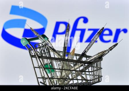 Medizinische Spritzen im Mini-Einkaufswagen sind vor dem Pfizer-Logo auf einem Bildschirm zu sehen. Am Freitag, den 28. Mai 2021, in Dublin, Irland. (Foto von Artur Widak/NurPhoto) Stockfoto