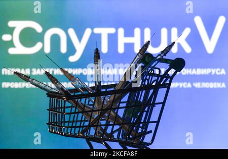 Medizinische Spritzen im Mini-Einkaufswagen sind vor dem Sputnik V-Logo auf einem Bildschirm zu sehen. Am Freitag, den 28. Mai 2021, in Dublin, Irland. (Foto von Artur Widak/NurPhoto) Stockfoto