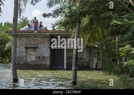 Eine Familie hat sich auf dem Dach unterbringen lassen, als die Flusswälle zerbrochen sind und mehrere Dörfer überschwemmt wurden. Am 28. Mai 2021 in South 24 Parganas, Westbengalen, Indien. Die Menschen in Westbengalen sind stark betroffen, da Flussdämme gebrochen sind und mehrere Dörfer aufgrund von Hochwasser und starkem Regen aufgrund des Super-Wirbelsturms YaaS überflutet wurden. (Foto von Dipayan Bose/NurPhoto) Stockfoto