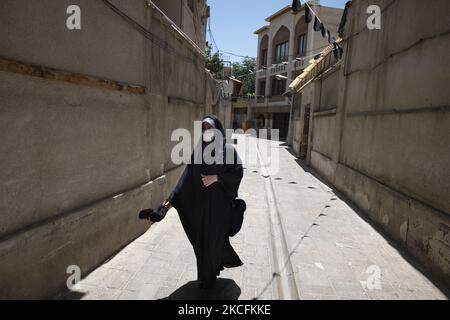 Eine verschleierte iranische Frau mit einer schützenden Gesichtsmaske geht während der Tage der Präsidentschaftswahlen am 4. Juni 2021 durch eine Gasse im Norden Teherans. (Foto von Morteza Nikoubazl/NurPhoto) Stockfoto