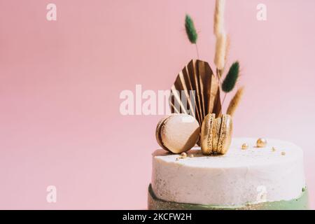 Spinatkuchen in weiß-grüner Farbe mit Makronen vor rosa Hintergrund Stockfoto