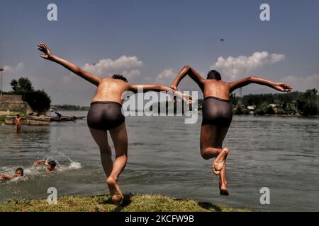 Kashmiri-Jungen kühlen sich am 09. Juni 2021 im Fluss Jehlum ab, um an einem heißen Sommertag in der Stadt Sopore im Distrikt Baramulla, etwa 60Kms von Srinagar in Jammu und Kaschmir, Indien, die Hitze zu besiegen. Während die anhaltende erste Hitzewelle des Jahres in Kaschmir in den nächsten zwei weiteren Tagen anhalten wird, wird davon ausgegangen, dass der Monsun die Region treffen und ab Juni 11 leichte Regenfälle mit sich bringen wird. Fast zwei Jahre seit der Aufhebung von Artikel 370 erlebt der Staat Jammu & Kaschmir in diesen Tagen eine hektische politische Aktivität. Quellen sagen, dass die Abgrenzungskommission wahrscheinlich den nördlichen Staat so besuchen wird Stockfoto