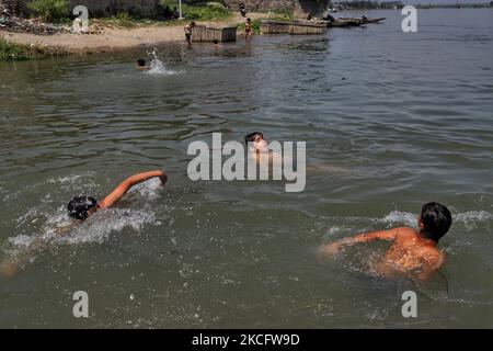 Kashmiri-Jungen kühlen sich am 09. Juni 2021 im Fluss Jehlum ab, um an einem heißen Sommertag in der Stadt Sopore im Distrikt Baramulla, etwa 60Kms von Srinagar in Jammu und Kaschmir, Indien, die Hitze zu besiegen. Während die anhaltende erste Hitzewelle des Jahres in Kaschmir in den nächsten zwei weiteren Tagen anhalten wird, wird davon ausgegangen, dass der Monsun die Region treffen und ab Juni 11 leichte Regenfälle mit sich bringen wird. Fast zwei Jahre seit der Aufhebung von Artikel 370 erlebt der Staat Jammu & Kaschmir in diesen Tagen eine hektische politische Aktivität. Quellen sagen, dass die Abgrenzungskommission wahrscheinlich den nördlichen Staat so besuchen wird Stockfoto