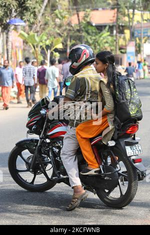 Frau auf einem Fahrrad trägt ein Paket getrockneter Kokosblütenhüllen (Kothumbu), das als Brennstoff für ein Feuer beim Kochen von Pongala während des Attukal Pongala Mahotsavam Festivals in der Stadt Thiruvananthapuram (Trivandrum), Kerala, Indien, am 19. Februar 2019 verwendet wird. Das Attukal Pongala Mahotsavam Festival wird jedes Jahr von Millionen Hindu-Frauen gefeiert. Während dieses Festivals bereiten Frauen Pongala (Reis gekocht mit Jaggery, Ghee, Kokosnuss sowie anderen Zutaten) im Freien in kleinen Töpfen zu, um der Göttin Kannaki zu gefallen. Pongala (was wörtlich bedeutet, überkochen) ist eine rituelle Darbringung eines Süßes Stockfoto