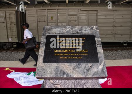 Ein Pendler kommt am 10. Juni 2021 an einer mit Marmor bemalten Granitgravur bemalten Tafel am neu in Betrieb genommenen Bahnhof Mobolaji Johnson in Ebutemeta, Lagos, Nigeria, vorbei. Präsident Muhammadu Buhari besuchte am Donnerstag Lagos zur Einweihung des 157 Kilometer langen Standardbahnprojekts Lagos-Ibadan am Bahnhof Mobolaji Johnson in Ebute Metta. Die Bauarbeiten begannen im März 2017 und die Testarbeiten begannen im Dezember 2020. Der Bahnhof Ebute Metta, bekannt als Mobolaji Johnson Station, ist der größte Bahnhof in Westafrika mit einer Haltekapazität von 6000 Passes Stockfoto