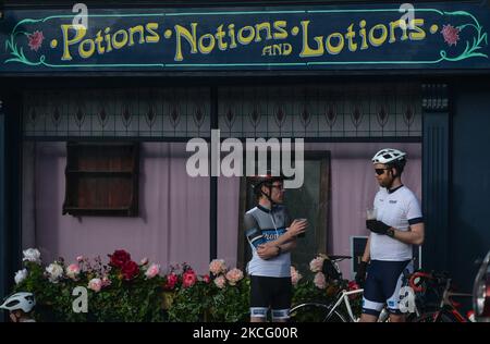 Zwei Radfahrer genießen einen Drink vor einer mit Blumen geschmückten lokalen Apotheke im Dorf Enniskerry, Co. Wicklow. Es sind nur noch zwei Tage, bis die Dreharbeiten für Disneys „enttäuschte“ Hauptrolle mit Amy Adams, Patrick Dempsey, James Marsden, Idina Menzel und Maya Rudolph beginnen. Ein Team von Zimmerleuten, Malern, Baumeistern und Dekorateuren hat den letzten Schliff gegeben, um Teile des Dorfes wie ein magisches Disney-Wunderland aussehen zu lassen. Am Freitag, den 11. Juni 2021, in Enniskerry, County Wicklow, Irland. (Foto von Artur Widak/NurPhoto) Stockfoto