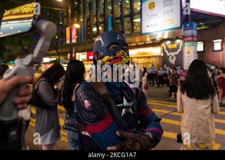 Ein Mann mit einem Captain America Kostüm posiert für Live-Streamer, nachdem er von der Polizei entlassen wurde. Adam Ma, ein weiterer Imitator von Captain America, wartet derzeit im Gefängnis nach dem nationalen Sicherheitsgesetz auf ein Gerichtsverfahren. Die Polizei war am 12. Juni 2021 erneut in den Bezirken Causeway Bay und Mongkok in Hongkong in Kraft, um jeden Versuch zu unterbinden, auf Aufrufe sozialer Medien zu reagieren, um zu protestieren und den 2.. Jahrestag der Proteste zu feiern, die die Bewegung 2019-2020 in Hongkong ins Leben gerufen haben. Nur wenige Menschen nahmen an dem Anruf Teil. Die Polizei hielt an und durchsucht jeden, den sie für verdächtig hielten. (Foto von Marc F Stockfoto