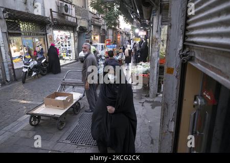 Eine verschleierte iranische Frau, die eine schützende Gesichtsmaske trägt, geht am 13. Juni 2021 in der Nähe eines Basars (Marktes) im Süden Teherans entlang einer Straße. Das iranische Volk wird am 18. Juni seine Stimme abgeben, um einen neuen Präsidenten zu wählen. (Foto von Morteza Nikoubazl/NurPhoto) Stockfoto