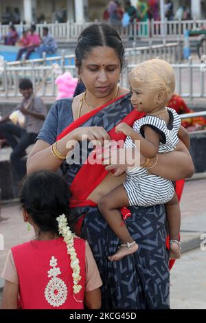 Frau hält ihr Kind, dessen Kopf im Rahmen eines Rituals im Thiruchendur Murugan Tempel in Thiruchendur, Tamil Nadu, Indien, rasiert und mit Sandelholzpaste bedeckt wurde. Dieser alte Hindu-Tempel, der Lord Murugan gewidmet ist, soll der Ort der Schlacht zwischen Lord Murugan und Soorapadman sein und der Ort, an dem Lord Muruga den Dämon Surapadma (Sooran) eroberte. Dieser Tempel ist einer der sechs Aboden von Murugan. (Foto von Creative Touch Imaging Ltd./NurPhoto) Stockfoto