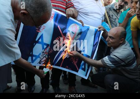 Palästinenser verbrennen ein Plakat, auf dem der israelische Premierminister Naftali Bennett während eines Protestes über eine Fahnenschwenkende Prozession von rechtsextremen israelischen Gruppen in und um die Altstadt von Ostjerusalem in Khan Younis im südlichen Gazastreifen abgebildet ist, am 15. Juni 2021. (Foto von Majdi Fathi/NurPhoto) Stockfoto