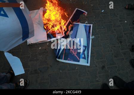 Palästinenser verbrennen ein Plakat, auf dem der israelische Premierminister Naftali Bennett während eines Protestes über eine Fahnenschwenkende Prozession von rechtsextremen israelischen Gruppen in und um die Altstadt von Ostjerusalem in Khan Younis im südlichen Gazastreifen abgebildet ist, am 15. Juni 2021. (Foto von Majdi Fathi/NurPhoto) Stockfoto