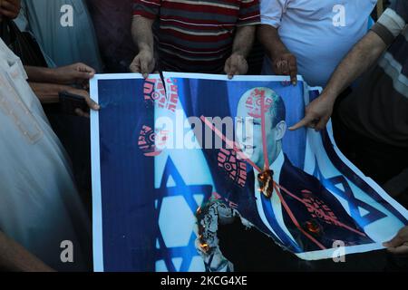 Palästinenser verbrennen ein Plakat, auf dem der israelische Premierminister Naftali Bennett während eines Protestes über eine Fahnenschwenkende Prozession von rechtsextremen israelischen Gruppen in und um die Altstadt von Ostjerusalem in Khan Younis im südlichen Gazastreifen abgebildet ist, am 15. Juni 2021. (Foto von Majdi Fathi/NurPhoto) Stockfoto