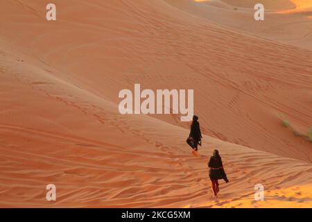 Beduinenfrauen wandern über die Sanddünen in der Erg Chebbi Wüste in der Nähe des kleinen Dorfes Merzouga in Marokko, Afrika. Merzouga ist ein Dorf in der Sahara in Marokko, am Rande von Erg Chebbi, einem 50km langen und 5km breiten Sanddünen-Set, das bis zu 350m erreicht. (Foto von Creative Touch Imaging Ltd./NurPhoto) Stockfoto