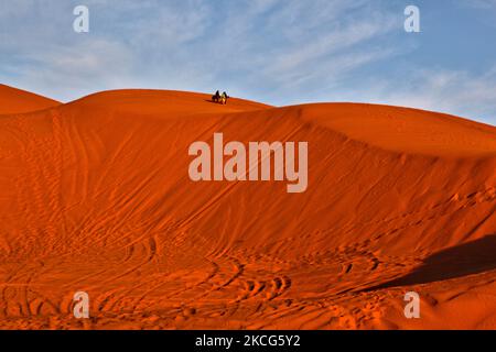 Beduinenfrauen wandern über die Sanddünen in der Erg Chebbi Wüste in der Nähe des kleinen Dorfes Merzouga in Marokko, Afrika. Merzouga ist ein Dorf in der Sahara in Marokko, am Rande von Erg Chebbi, einem 50km langen und 5km breiten Sanddünen-Set, das bis zu 350m erreicht. (Foto von Creative Touch Imaging Ltd./NurPhoto) Stockfoto