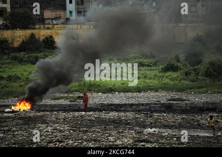 Giftiger Rauch tritt aus einem Plastikhaufen hervor, der am 18. Juni 2021 in der Nähe des alten Buriganga-Flusskanals bei Sonnenaufgang in Dhaka, Bangladesch, brennt. (Foto von Syed Mahamudur Rahman/NurPhoto) Stockfoto