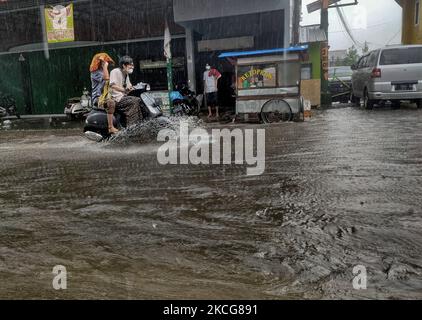 Nach heftigen Regenfällen am 18. Juni 2021 in Bogor Regency, West Java, Indonesien, machen sich Pendler auf den Weg entlang einer wasserdichten Straße. (Foto von Adriana Adie/NurPhoto) Stockfoto