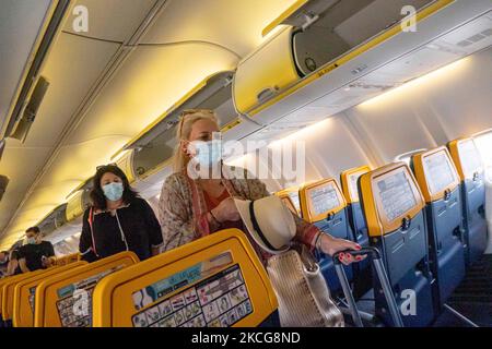 Passagiere tragen während des Fluges eine Gesichtsbedeckung in der Kabine. Fliegen während der Coronavirus-Pandemie Covid-19 in einer Boeing 737-800 der Billigfluggesellschaft Ryanair mit Ziel Chania auf Kreta, einem beliebten Urlaubsziel. Im Flugzeug ist es obligatorisch, Gesichtsmasken für die Passagiere und die Flugbesatzung, die Flugbegleiterin usw. zu tragen, während die Menschen als Sicherheitsmaßnahme einen negativen COVID-Test benötigen, um an Bord zu gehen, während die Luft- und Tourismusindustrie sich bemüht, zur Normalität zurückzukehren. Griechenland versucht, seinen Tourismus anzukurbeln und Privilegien für Impfungen gegen Cov zu geben Stockfoto